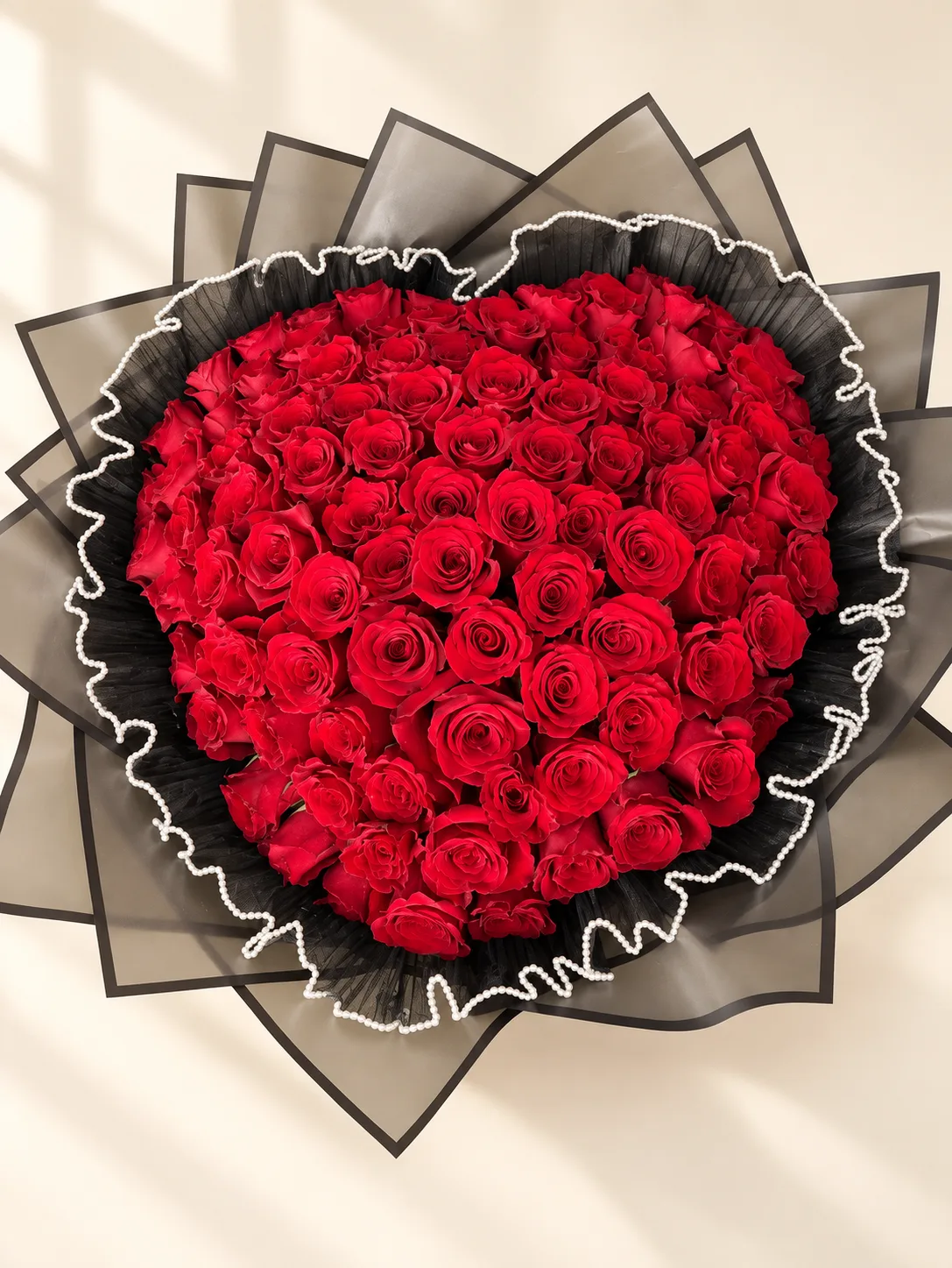 Ramo abundante de rosas rojas con envoltura oscura